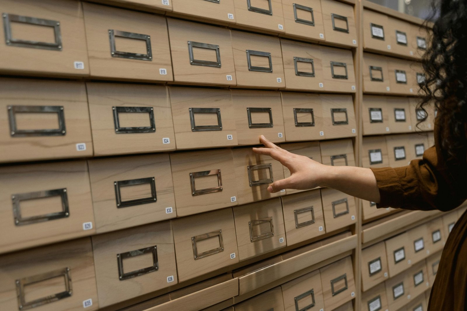 A Person Standing Near Data Base Wooden Drawer