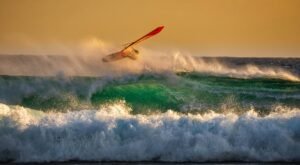 Windsurfer catching air on vibrant waves at sunset in Paleochora, Greece.