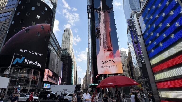 Times Square with SpaceX and Nasdaq billboards, SPCX Nasdaq listed, rocket launch image, people and vehicles on street.