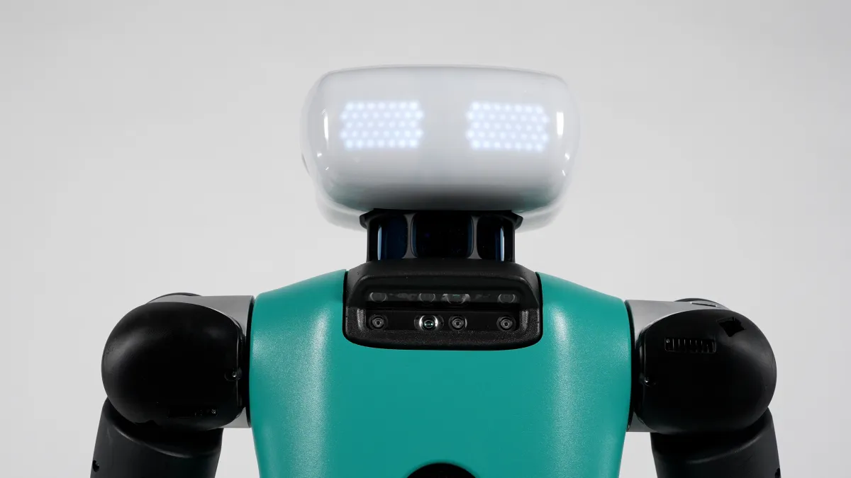 Robot with a teal body and black joints, featuring a white head with glowing lights, against a plain background.