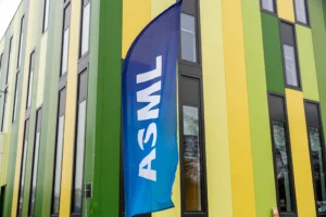 Blue ASML flag outside a building with green and yellow vertical stripes, multiple windows visible.