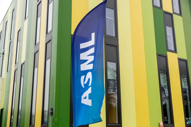 Blue ASML flag outside a building with green and yellow vertical stripes, multiple windows visible.