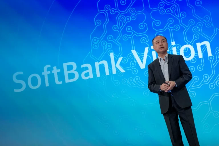 Man in a suit stands on stage with a blue circuit pattern background and "SoftBank Vision" text.