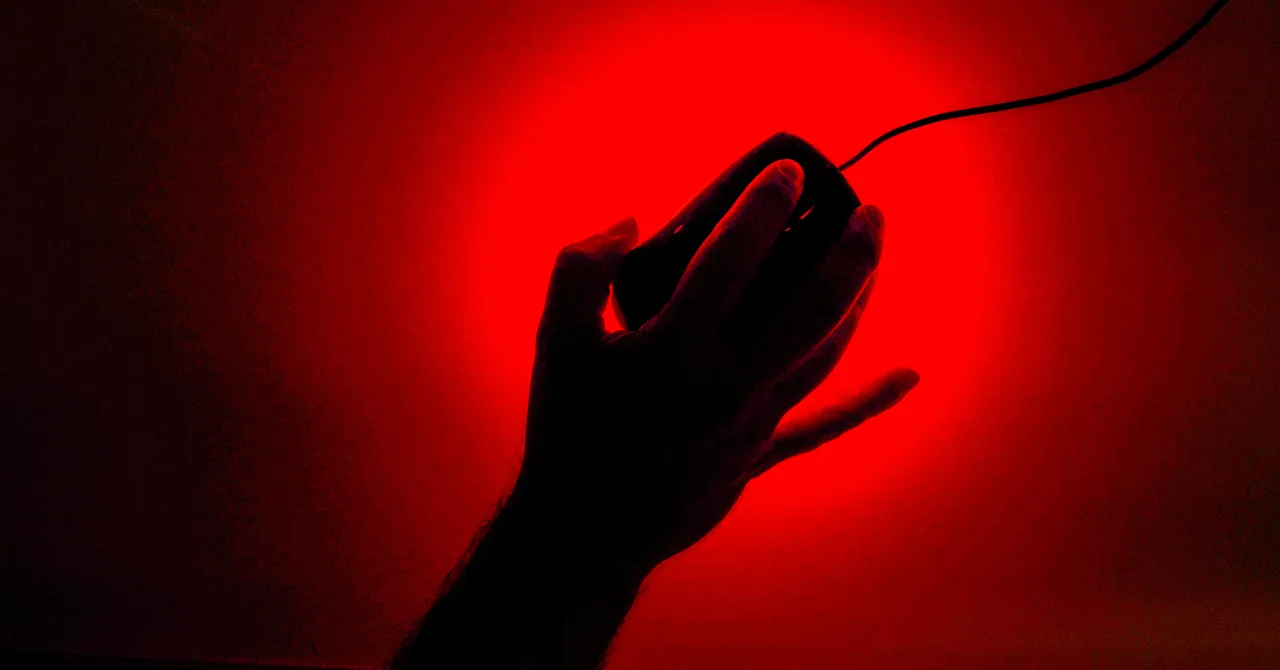 Silhouette of a hand holding a computer mouse against a bright red background.