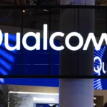 Qualcomm logo displayed on a large digital screen in a tech exhibition setting.