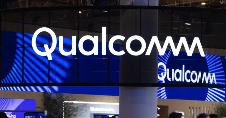Qualcomm logo displayed on a large digital screen in a tech exhibition setting.
