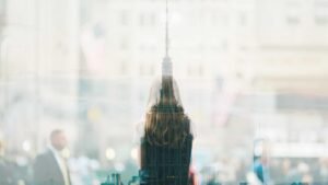 Double exposure of a woman facing away and a cityscape with skyscrapers, blurred crowd in the background.
