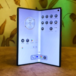 Foldable smartphone displaying apps and a clock interface, set against a floral wallpaper background.