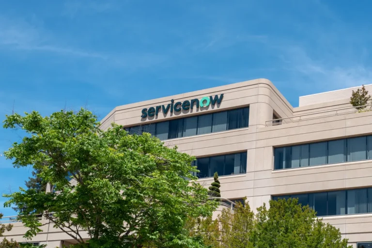 ServiceNow building with logo, surrounded by trees, under a clear blue sky.