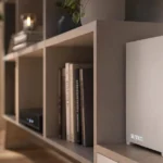 Sleek white device labeled Sunrun on a modern shelf with books and decor, soft lighting, blurred background with couch