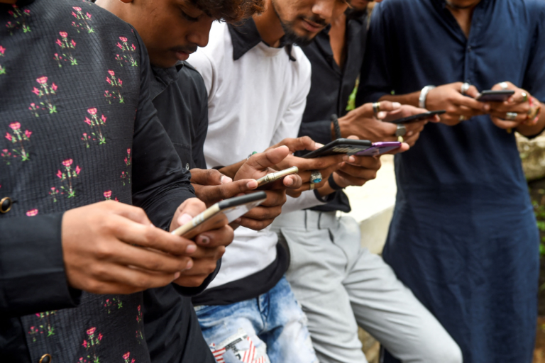 Group of people standing closely together using smartphones outdoors