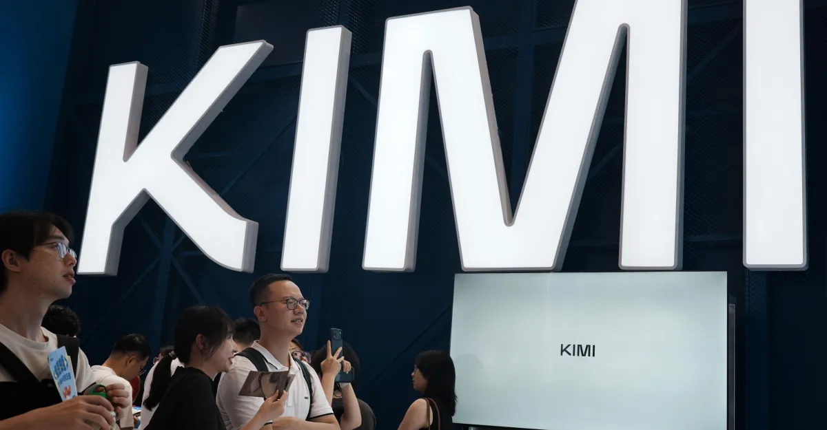 People gather near a large illuminated "KIMI" sign, with some holding phones and tablets.