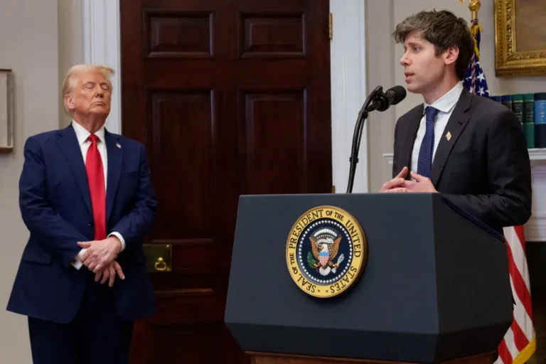 Two men in suits at a podium with the U.S. presidential seal, one speaking into a microphone. American flag in the backgro...