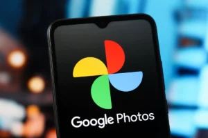 Smartphone screen displaying Google Photos logo with a colorful pinwheel icon, blurred background.