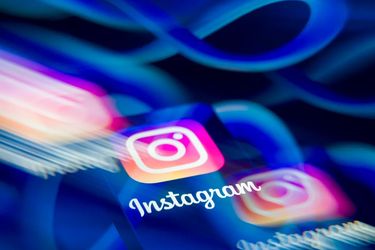 Instagram logo with vibrant colors and motion blur, set against a blue background with Meta's infinity symbol.
