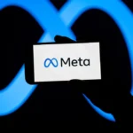 Hand holding a smartphone displaying the Meta logo, with a large blue Meta symbol in the background