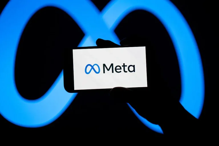 Hand holding a smartphone displaying the Meta logo, with a large blue Meta symbol in the background