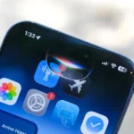 Close-up of a smartphone screen showing app icons, notifications, and a Siri activation graphic near the top.