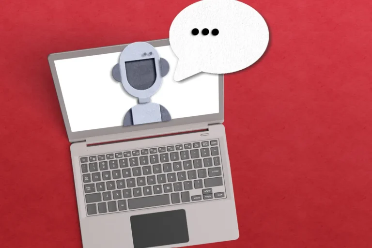 Laptop with a robot icon on screen and a speech bubble with ellipsis on a red background.