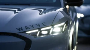 Close-up of a car's front with bright headlights and "Wayve" logo on the hood.