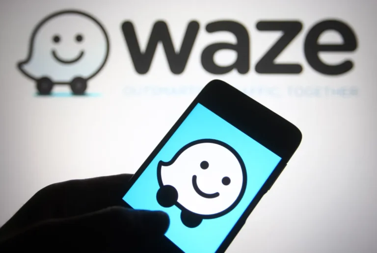Waze logo displayed on a smartphone screen in front of a larger Waze logo backdrop.