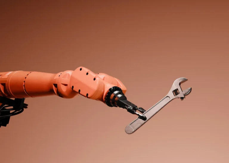 Robotic arm holding an adjustable wrench against a gradient brown background.