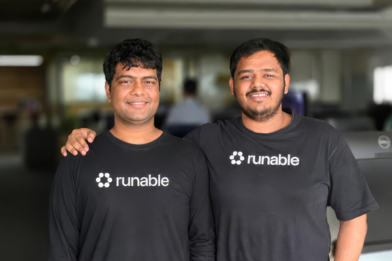 Two smiling individuals in black shirts with "runable" logo, standing in an office environment.