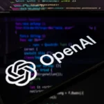 OpenAI logo on a phone screen with computer code in the background.