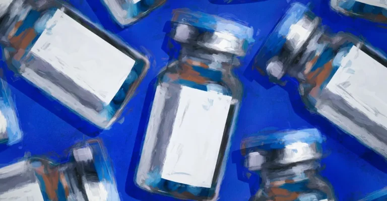 Multiple vaccine vials with blank labels on a blue background.