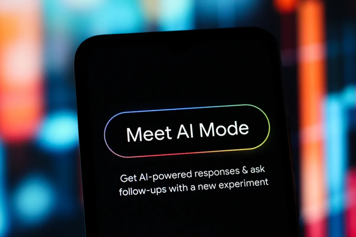 Smartphone screen displaying "Meet AI Mode" with a prompt about AI-powered responses, set against a blurred colorful backg...