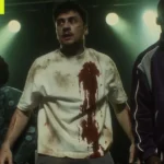 Three men under stage lights, one with a bloodstained shirt, labeled as AI-generated image in the corner.