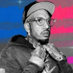 Man in a cap and glasses with tattoos, holding a chain, against a colorful background with waveforms and sparkles.