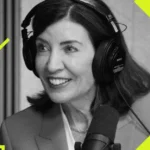 Woman in headphones speaking into a microphone, geometric yellow shapes overlayed, grayscale image.