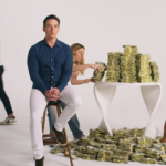 Man sitting on stool, two people stacking and collecting bundles of cash from table and floor, another person walking by.