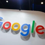 Google logo in large colorful letters on a white wall, with spotlights in the background.