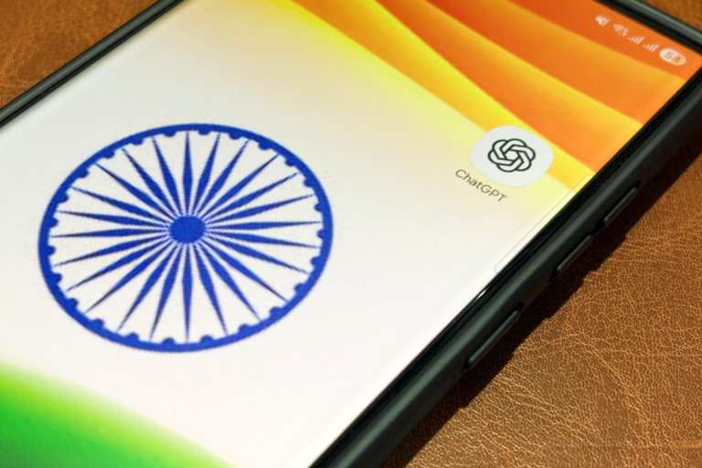 Smartphone screen displaying the ChatGPT app icon next to the Indian flag's Ashoka Chakra on a leather surface.