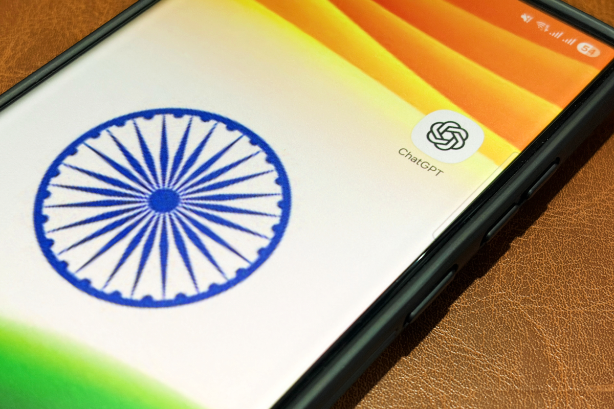 Smartphone screen displaying the ChatGPT app icon next to the Indian flag's Ashoka Chakra on a leather surface.