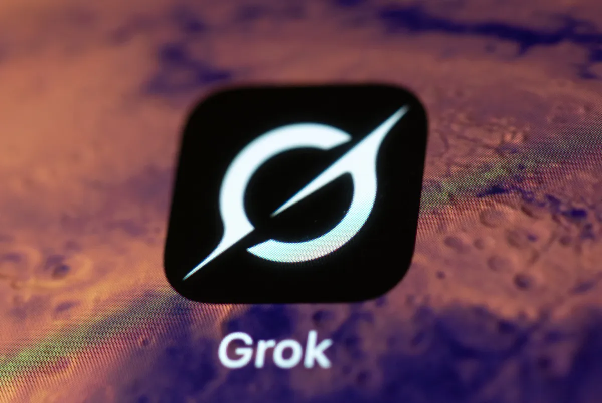 Grok app icon on a smartphone screen, featuring a stylized white symbol on a black background, with the word "Grok" below it.