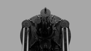 Top view of a complex, cylindrical industrial structure with multiple pipes and components against a gray background.