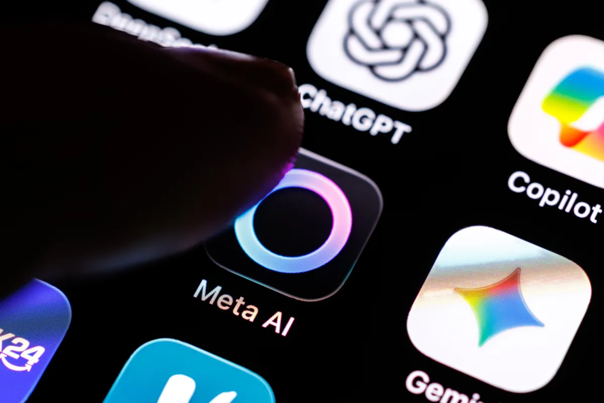 Finger touching Meta AI app icon on a smartphone screen, with other app icons visible including ChatGPT and Copilot.