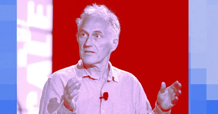 Man speaking with hands raised, wearing a light shirt and microphone, set against a red and blue background.