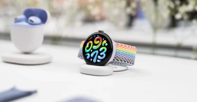 Smartwatch with colorful woven band on a charging stand, displaying vibrant numbers; earbuds case in the background.