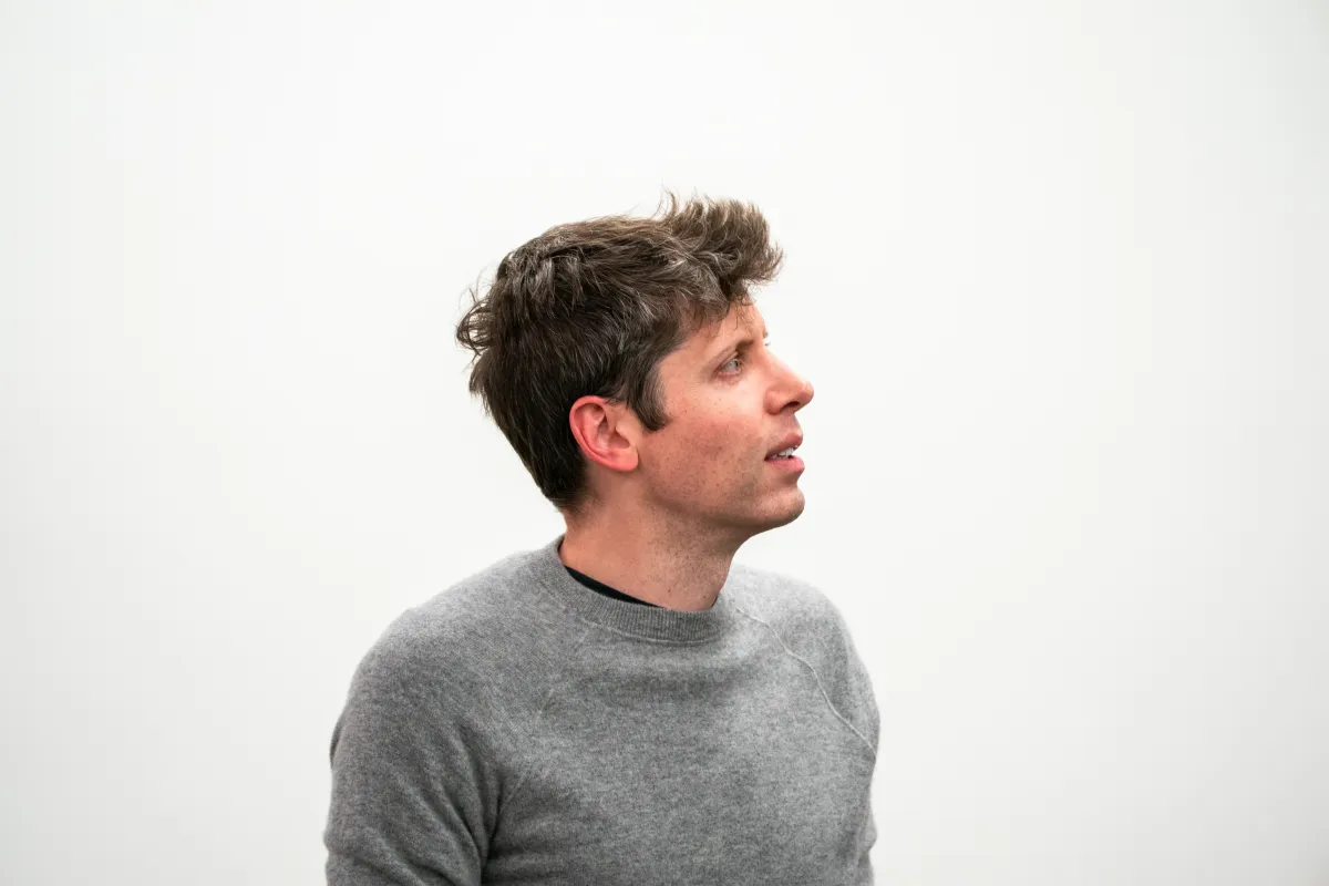 Man in a gray sweater looking to the side against a plain white background.