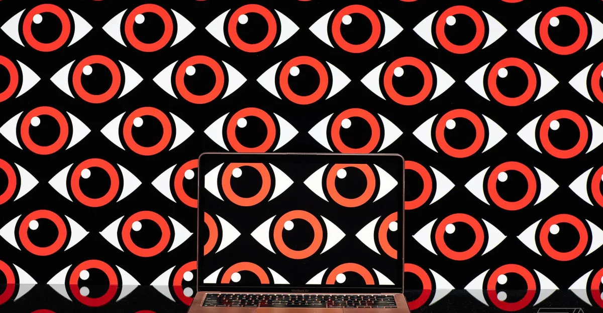 Laptop displaying red and white eye pattern, matching the background, symbolizing surveillance or scrutiny.