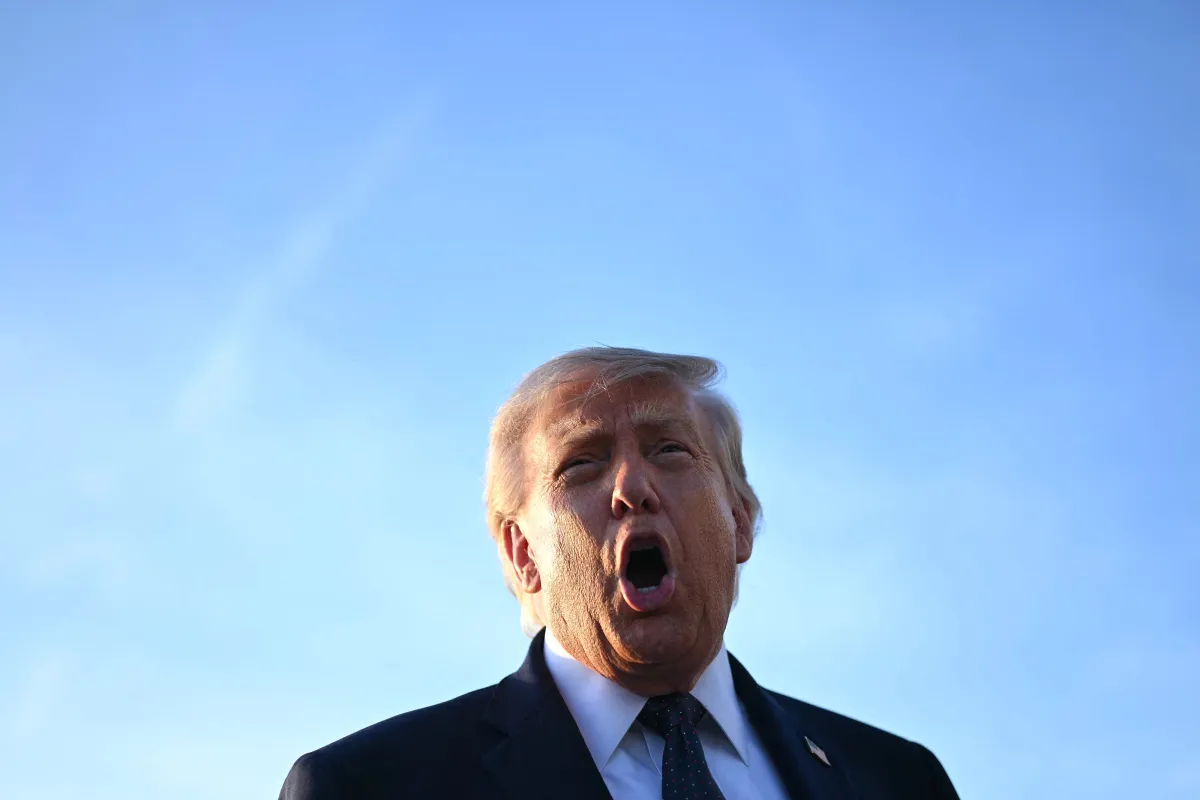 A man in a suit speaks passionately against a clear blue sky.