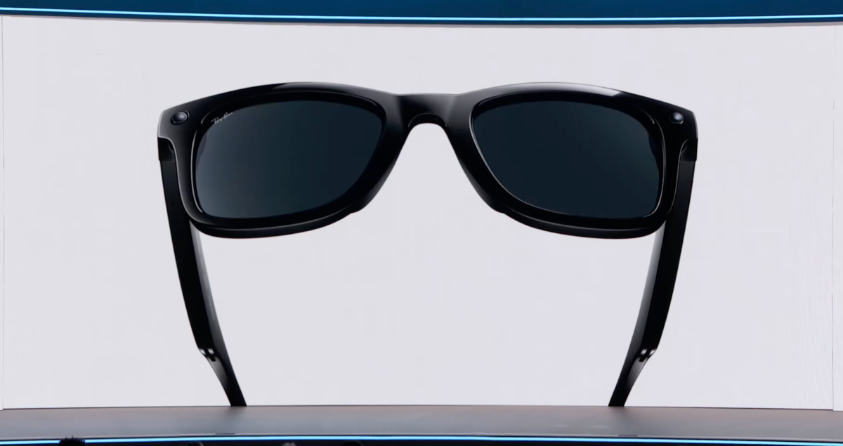Black sunglasses with dark lenses on a white background, displayed on a blue-bordered platform.