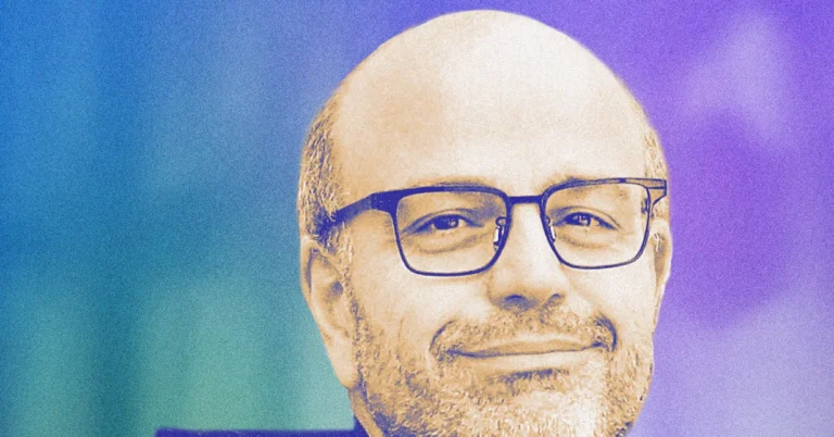 Man with glasses smiling against a gradient blue and purple background.