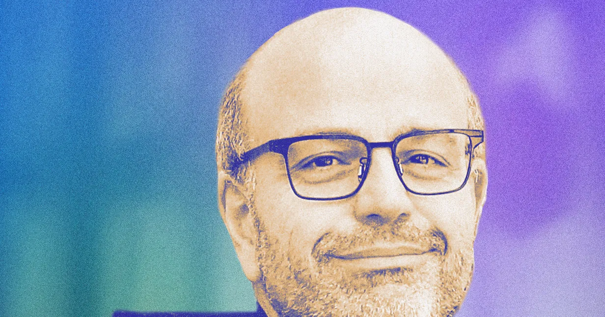 Man with glasses smiling against a gradient blue and purple background.