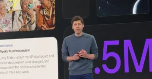 Man in a gray sweater speaks on stage with slides showing elderly women using a smartphone and text about a weekly busines...