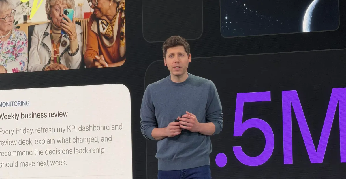 Man in a gray sweater speaks on stage with slides showing elderly women using a smartphone and text about a weekly busines...